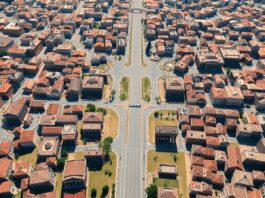 Aerial view of an ancient Roman city with grid streets, classical buildings, forums, temples, and aqueducts under a bright sky in a realistic style.